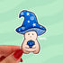 A sticker in the shape of a wizard mushroom character. The mushroom cap is blue with white stars and spirals. The magician holds a 20-sided die, used in tabletop games, and has rolled a 1.