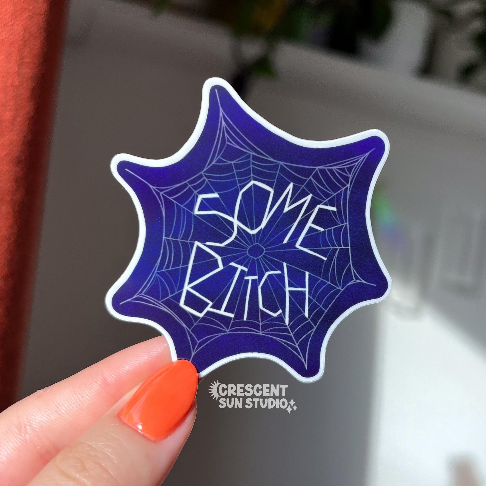 The words "some bitch" look as though they are woven into a spider web in this die cut sticker.