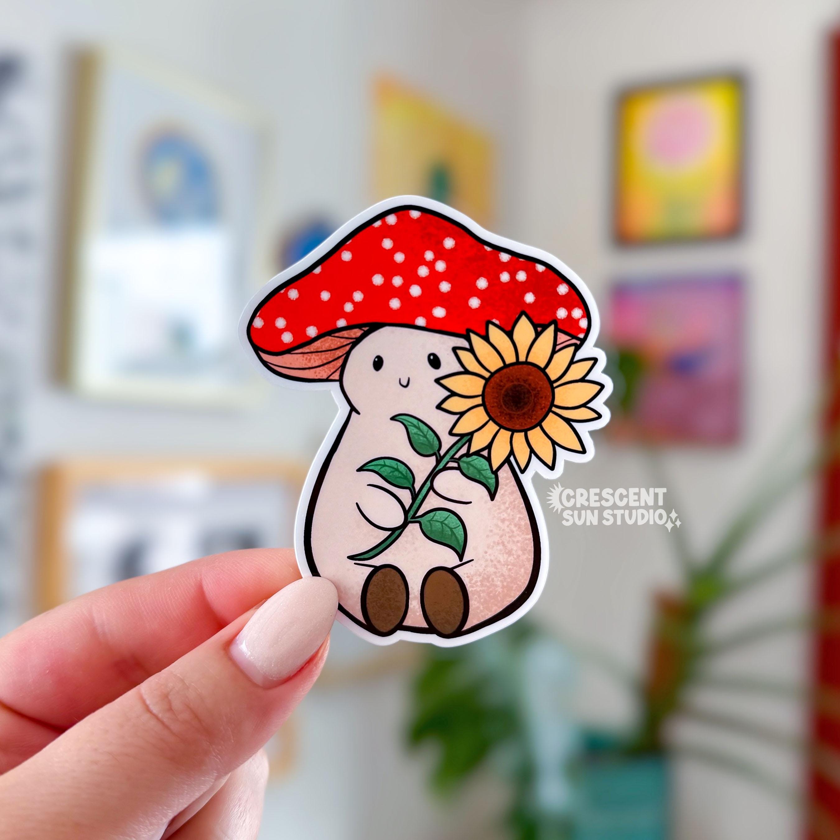 Stoney the Mushroom is a plump, smiling pinky-beige mushroom character with a red mushroom cap with white spots. Stoney is holding a large sunflower in his hands.
