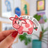 A pink cow with darker pink spots has two strawberries at the top of her head, as if they were horns, as well as a strawberry at the end of her tail. Above the cow's back it reads in black lettering "not in the mooooooood"