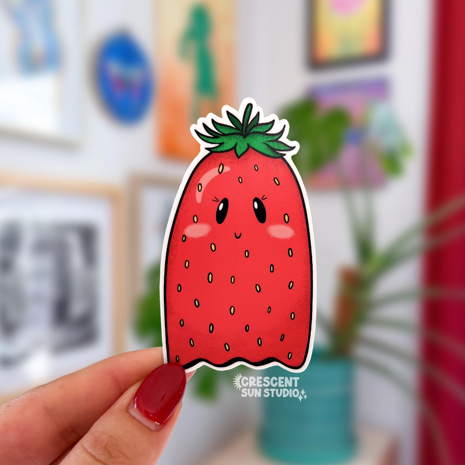 Die-cut sticker of a kawaii strawberry shaped like a ghost, with small eyes, pink cheeks, and a smile.