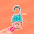 Die-cut water-resistant sticker of a smiling terracotta pot holding a green and pink succulent with a long arching bloom stem topped with small pink and orange flowers.