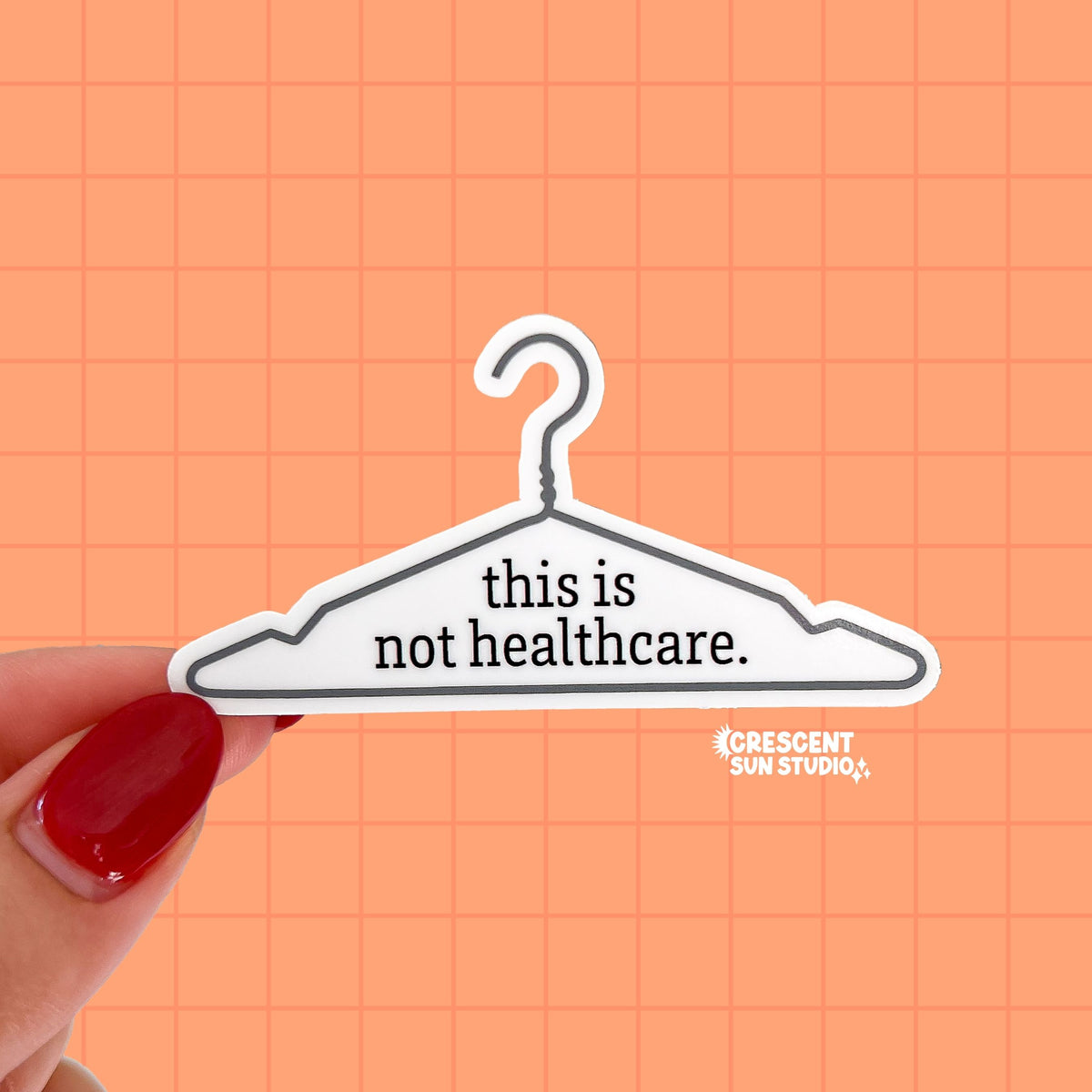 A die cut sticker of a wire hanger. In the center reads the text "this is not healthcare"