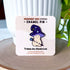 An enamel pin in the shape of a mushroom with an oversized mushroom cap that hooks to one side. The happy beige mushroom is holding a want with a crystal and moon on one end. His hat is purple with stars and spirals. In this image, the pin is displayed on a light colored card.