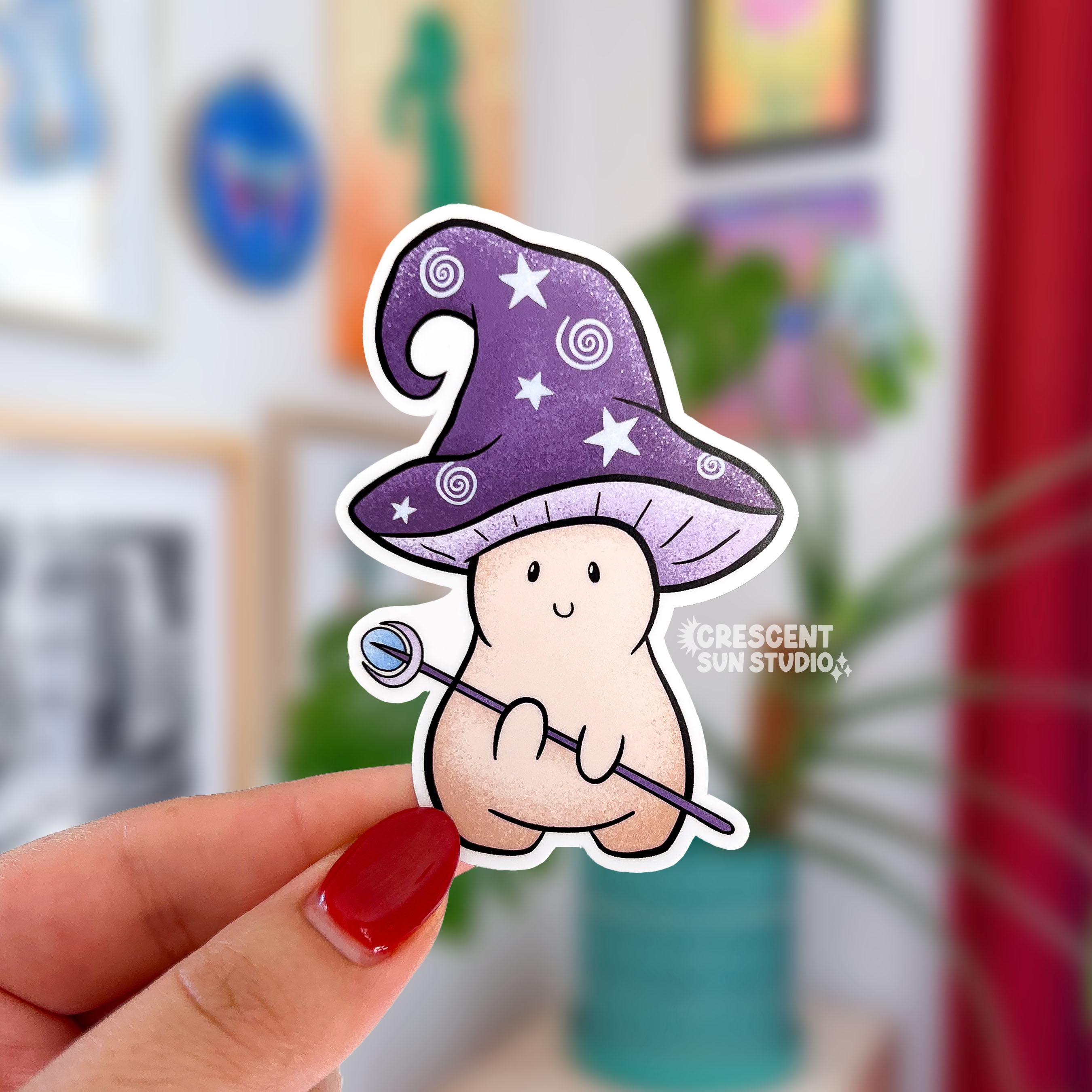 A sticker in the shape of a mushroom with an oversized mushroom cap that hooks to one side. The happy beige mushroom is holding a want with a crystal and moon on one end. His hat is purple with stars and spirals.