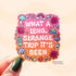 Die-cut sticker with a pink to orange gradient background reading 'What a Long Strange Trip It's Been' in white lettering surrounded by illustrated mushrooms, flowers with eyes, snails, a butterfly, and a worm.